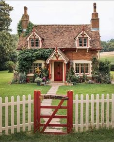 a red gate is in front of a brick house with ivy growing on the roof