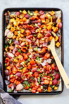 a pan filled with chopped vegetables and a wooden spoon