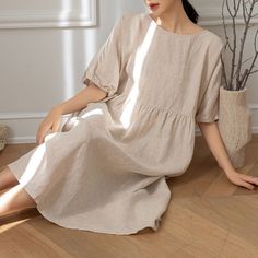 a woman is sitting on the floor wearing a dress and holding a potted plant