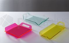 three different colored serving trays on a white surface