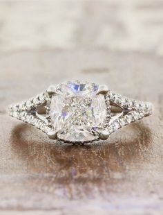 a cushion cut diamond ring with diamonds surrounding it