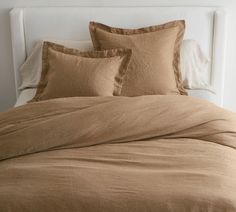 an unmade bed with brown linens and pillows