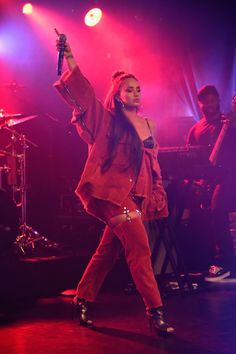 the woman is dancing on stage with her arms in the air