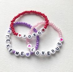 three beaded bracelets with words and hearts are shown on a white tablecloth