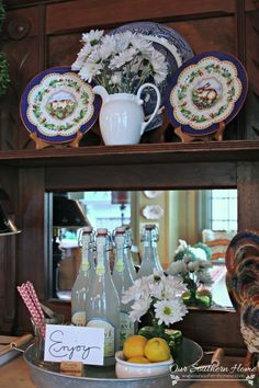 plates and vases are sitting on top of a china hutch with flowers in the center