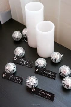 disco balls and name tags on a table with a white candle next to them in the background