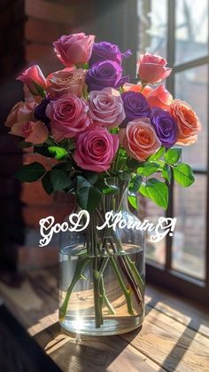 a vase filled with pink, purple and orange roses on top of a wooden table