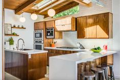 a kitchen with wooden cabinets and white counter tops next to an island in the middle