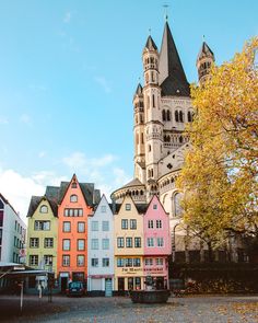 colorful buildings line the street in front of a tall building with spires on top