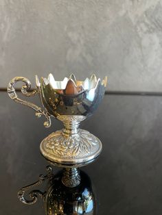 an ornate silver bowl sitting on top of a black table