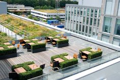 an outdoor seating area on the roof of a building with green plants growing in it