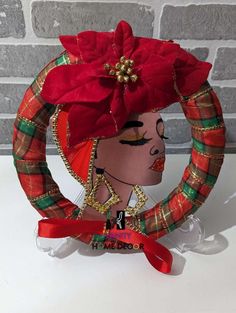 a paper doll wearing a red hat with gold trims and a poinsettia