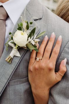 a person wearing a suit and tie with a flower on their lapel, holding onto his jacket