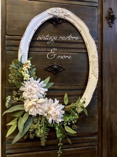 a white wreath with flowers hanging on the front door