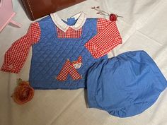 Vintage 70's Tiny Tots Originals, Blue/Red checkered Quilted infant set, 9-12 months, Looks like Raggedy Ann & Andy fabric & style! Adorable blue quilted top w/red & white checkered sleeves, button on cuff/wrist, white collar w/red stitiching & 2 buttons in front, Blue Quilted top stitched in red, cute stitched patch of red & white checkered child, back opening w/3 buttons, (sleeves sewn into quilted top, one piece)  Blue rubber bottom, elastic waist, rubber pant lining, pulls up (no snap button opening) Infant approx. 9-12 months (no size tag), maker tag-Tiny Tots Originals, In Beautiful Vintage Coondition, fabric still feels crisp & colors still vibrant! *shoulder to shoulder-9'inches across, *Chest-11' inches across, *Shoulder to hem-11' inches, *Rubber pant-6' inches, waist stretches u Blue Cotton Patchwork Sets, Plaid Cotton Playtime Set, Cute Plaid Cotton Sets, Cute Plaid Playtime Sets, Cute Gingham Sets For Playtime, Cute Gingham Playtime Sets, Vintage Blue Long Sleeve Sets, Fitted Gingham Cotton Sets, Vintage Sets For Spring Playtime