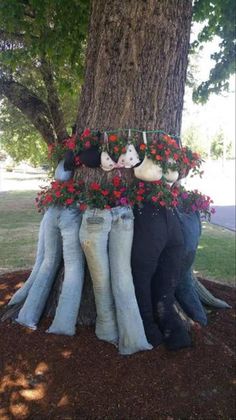 two people are sitting on the trunk of a tree with flowers growing out of them