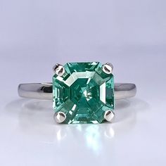 an emerald colored ring on a white surface