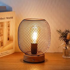 a lit candle sitting on top of a wooden table next to a book and vase