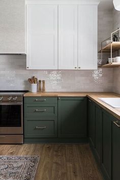 a kitchen with green cabinets and white cupboards on the wall, wood flooring