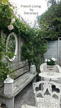 there is a bench, table and chairs in this garden area with roses on the fence