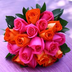 a bouquet of orange and pink roses sitting on top of a table