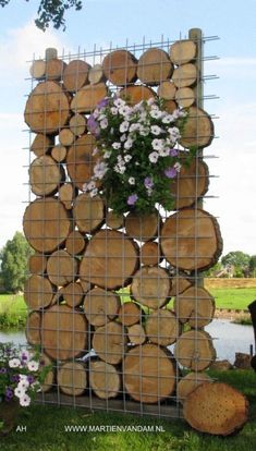 a bunch of logs stacked on top of each other with flowers in the center and hanging from them