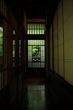 an empty hallway with wooden doors and green plants in the window sill, at night