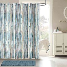 a bathroom with a blue rug and shower curtain