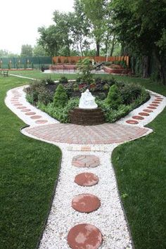 a brick walkway with stepping stones leading up to a fountain in the middle of a grassy area