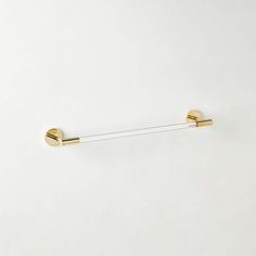 a pair of gold - plated hooks hang on a white wall