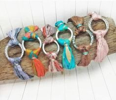 several different colored tassels are on a piece of driftwood, and one is tied to a hook