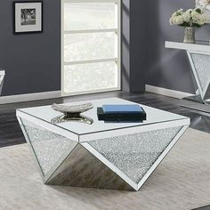 a modern coffee table with mirrored top in a living room setting on carpeted flooring