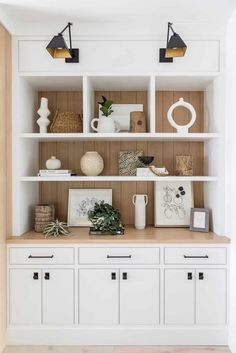 a white bookcase filled with lots of books and vases on top of it