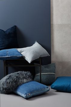 pillows and cushions are arranged on the floor next to a blue wall in a room