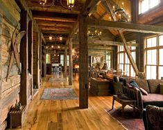 the inside of an old log cabin with wood floors and exposed beams, chandeliers and windows