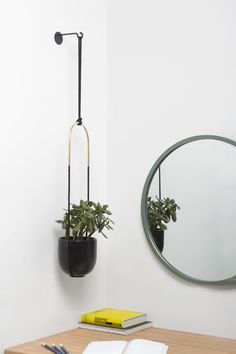 a desk with a mirror and plant on it next to a book, pen and notebook