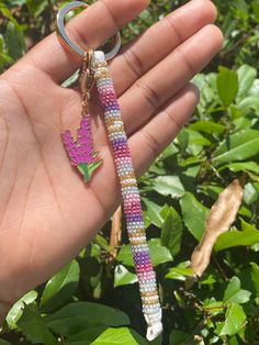 a hand holding a beaded keychain with a flower on it