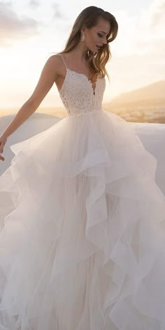 a woman in a wedding dress standing on top of a hill