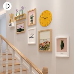 there are many framed pictures on the wall with a clock above them and below it is a staircase