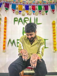 a man sitting on top of a cake covered in hendi dots with his hands painted