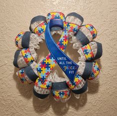 a blue ribbon is attached to a wreath made out of colorful pieces of puzzles