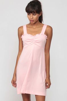 "Vintage 70s babydoll dress in baby pink with ruffled trim and an empire waist. Mini length. Every item we sell is authentic vintage and one-of-a-kind! You will receive the EXACT item shown in the photos. For reference, model is 5'7\" and measures 31-23-33. DETAILS Best fits: Extra small to Small (Note: We only have ONE in stock. If more than one size is listed it is because this item will work on a range of sizes. Check measurements for exact fit.) Condition: Very good vintage. Has a couple fai Daywear Coquette Ruffle Dress, Coquette Ruffle Dress For Daywear, Coquette Ruffled Day Dresses, Feminine Pink Mini Dress With Ruffled Straps, Sleeveless Ruffled Mini Dress In Coquette Style, Sleeveless Coquette Mini Dress With Ruffles, Coquette Sleeveless Mini Dress With Ruffles, Pink Ruffled Mini Dress For Daywear, Cute Ruffled Mini Dress For Daywear