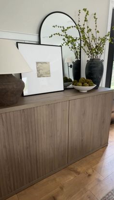 a wooden cabinet sitting in front of a mirror on top of a hard wood floor