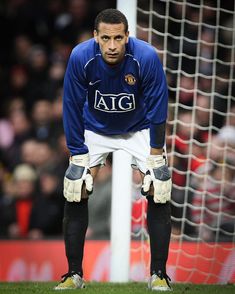 a soccer player is standing in front of the goalie's net with his hands on his knees