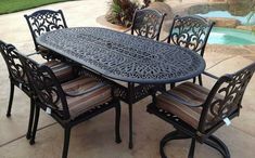 an outdoor dining table and chairs near a pool