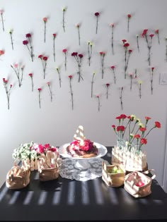 a table topped with cakes and flowers next to a wall hanging on the wall behind it