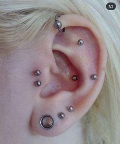 a close up of a person's ear with piercings on it and two balls in the middle