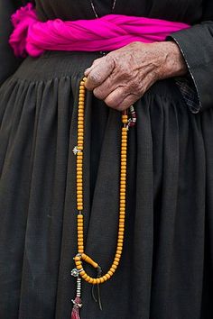 an old woman wearing a long beaded necklace with beads and tassels on her waist