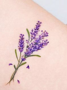 a small purple flower tattoo on the back of a woman's arm