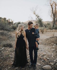 a young man and woman holding a baby in their arms while walking through the desert